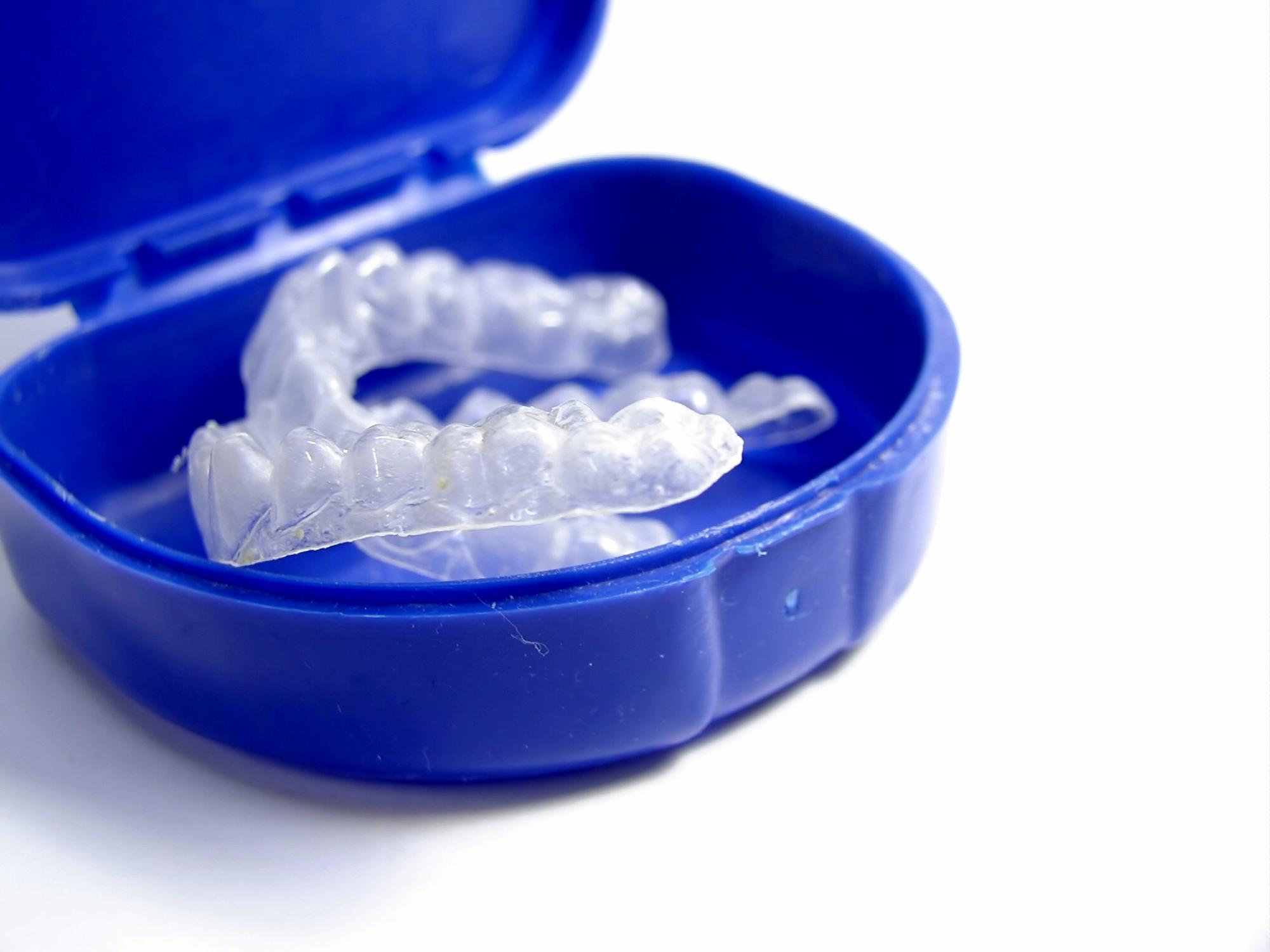 Clear dental retainers in a blue case, representing Freytag Orthodontics' Digital Retainer Guarantee for maintaining smiles.